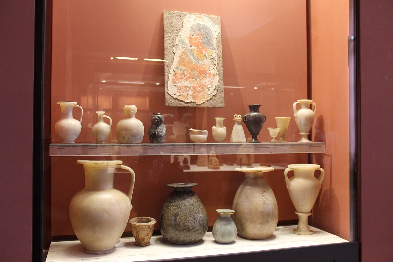 Ancient Egyptian stone vessels displayed with a painted fragment