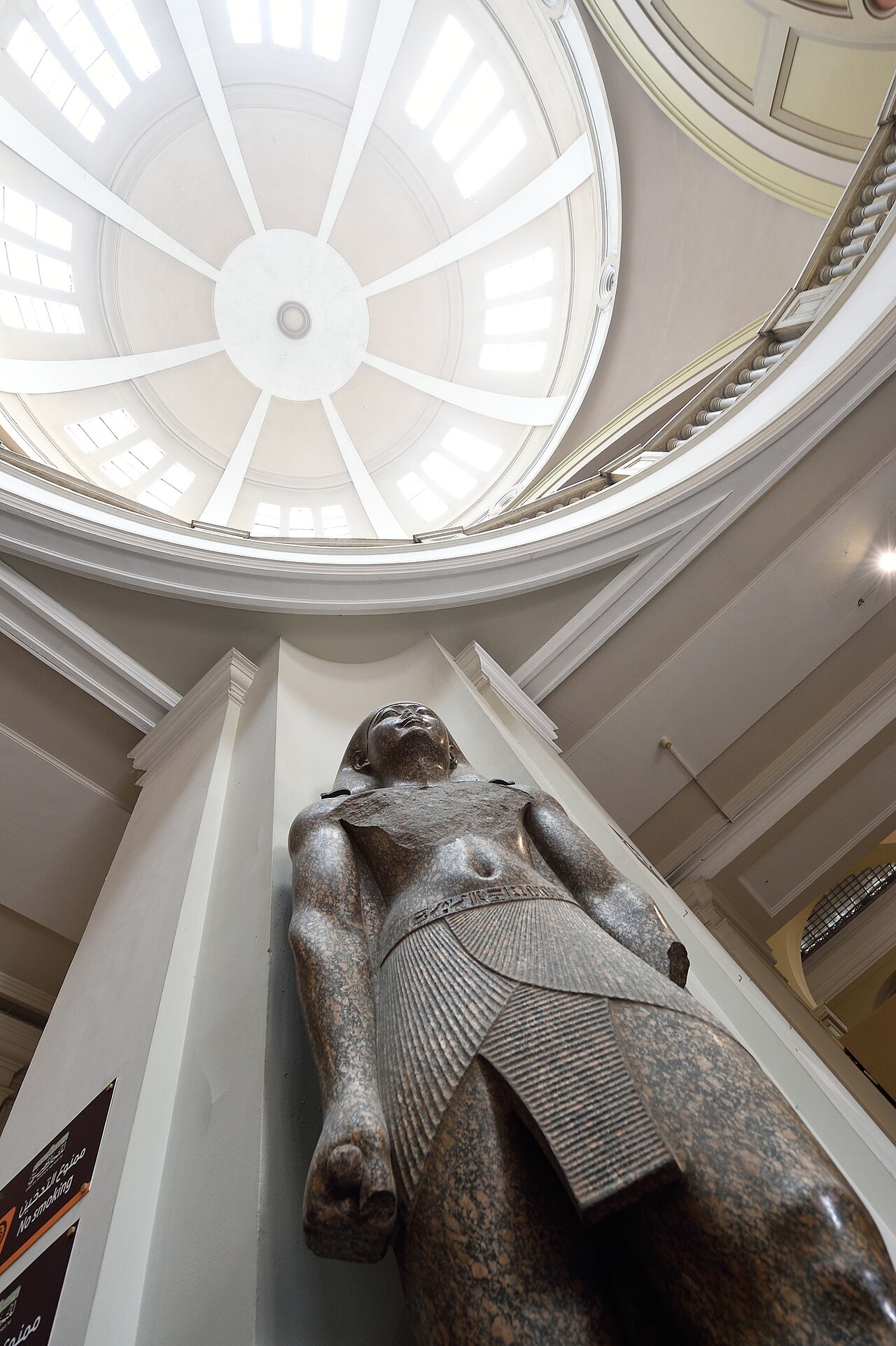 Large statue displayed beneath the historic ceiling of the Egyptian Museum in Cairo